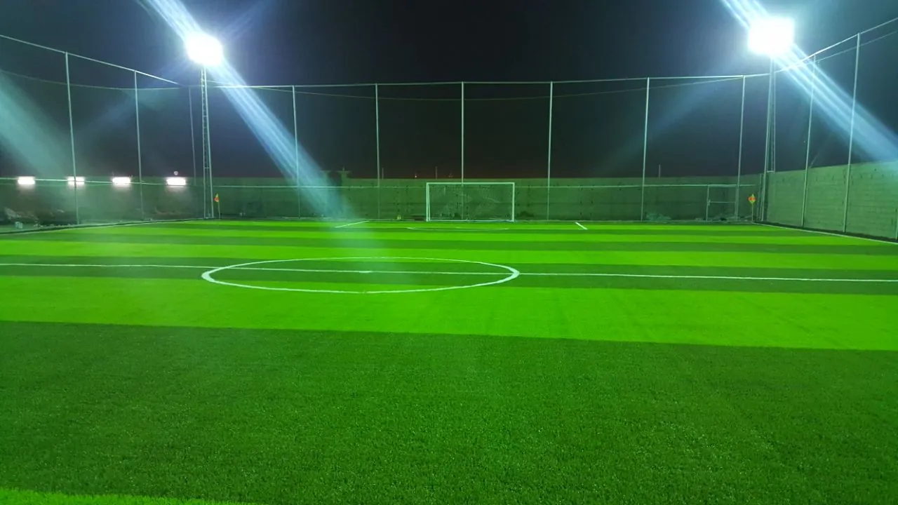 ملعب كرة قدم خماسي بعشب صناعي مضاء بكشافات LED ليلًا