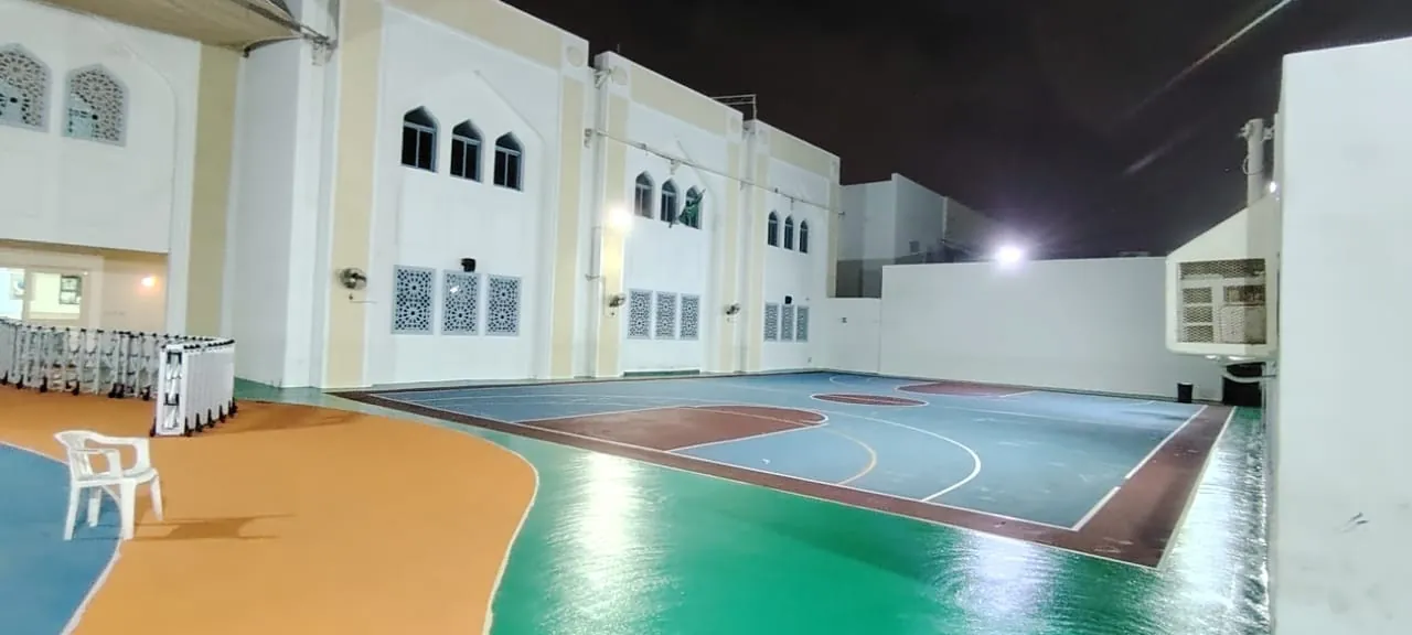ساحة رياضية بأرضية ملونة وخطوط ملاعب وإنارة ليلية